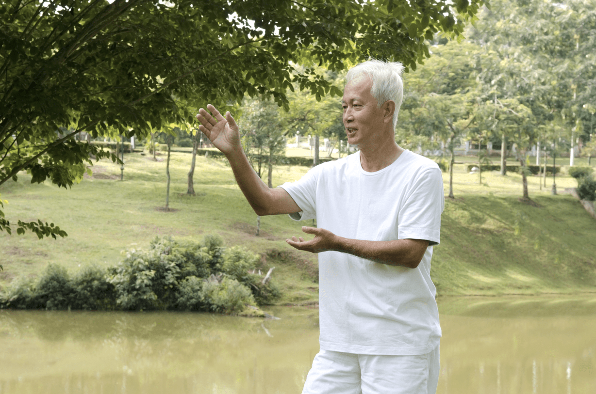 Homme mature faisant du qi gong dans un parc